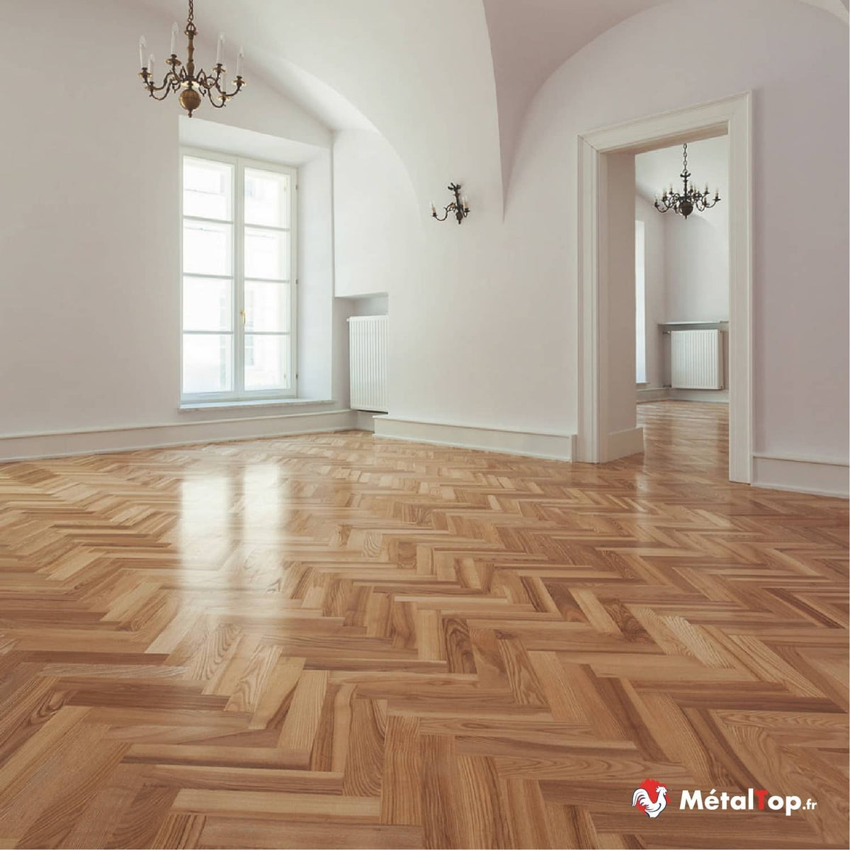 Parquet en chevrons en bois clair dans une pièce vide aux murs blancs, avec lustre et fenêtre