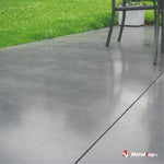 Terrasse en béton gris poli, pied de chaise en métal, pelouse verte et jardinière blanche en arrière-plan