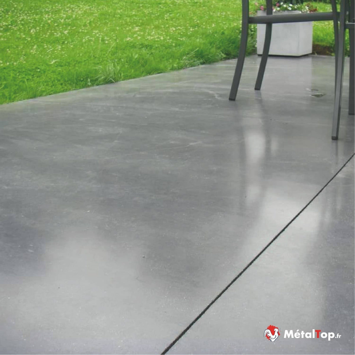 Terrasse en béton gris poli, pied de chaise en métal, pelouse verte et jardinière blanche en arrière-plan