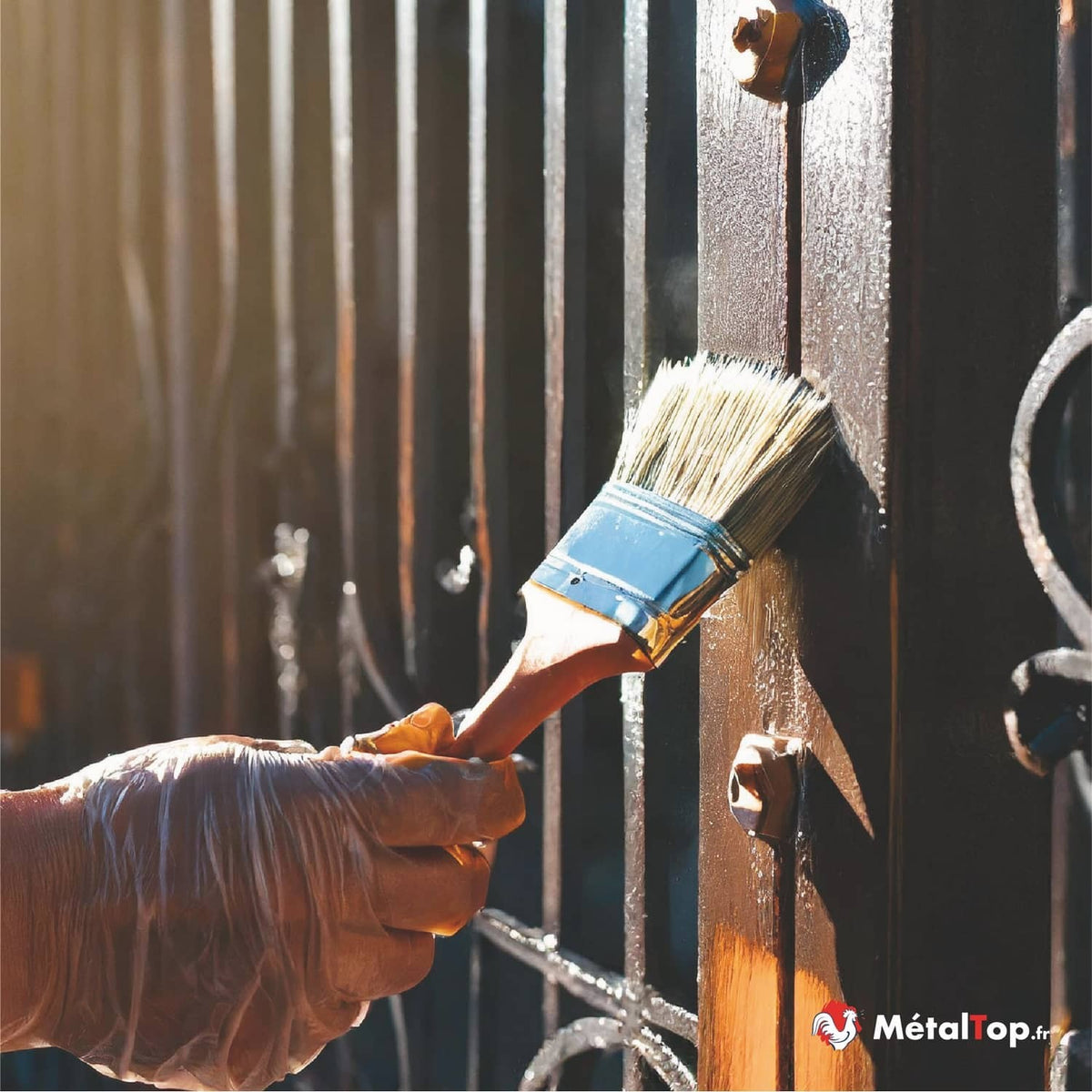 Application de peinture noire au pinceau sur un portail en fer forgé
