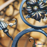 Détail de grille en fer forgé noir et doré avec fleur ornementale et volutes en spirale