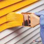 Application de peinture jaune au pinceau sur un bardage blanc horizontal