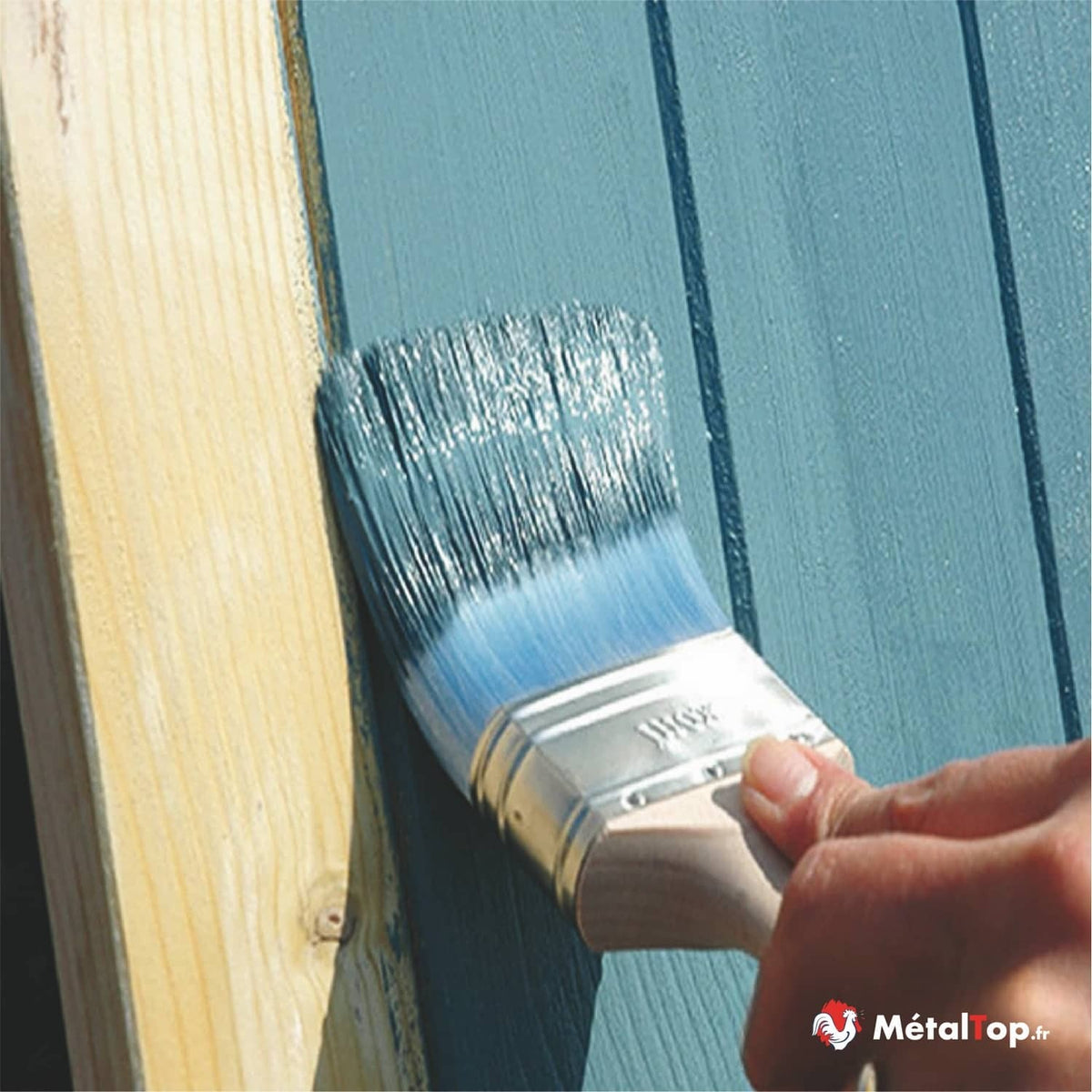Application de peinture bleue au pinceau sur des lames de bois verticales