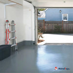 Garage au sol peint en gris brillant, avec une échelle et un bac de rangement, porte ouverte