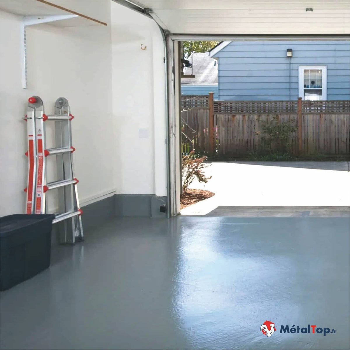 Garage au sol peint en gris brillant, avec une échelle et un bac de rangement, porte ouverte
