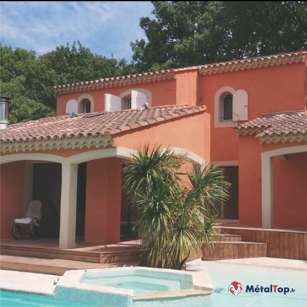 Villa aux murs orangés et toit en tuiles, avec piscine et palmier au premier plan