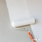 Rouleau à peinture blanche appliquant de la peinture sur un mur, manche orange