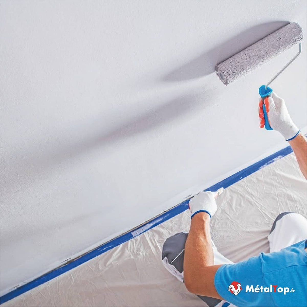 Peintre appliquant de la peinture blanche au rouleau sur un mur avec ruban de masquage bleu