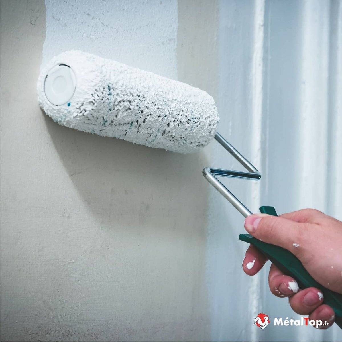 Rouleau à peinture blanc appliquant de la peinture sur un mur, près d'un encadrement de porte blanc