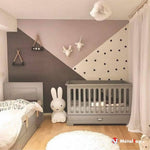 Chambre d'enfant avec lits gris, mur à motifs géométriques rose, taupe et pois noirs, lapin blanc