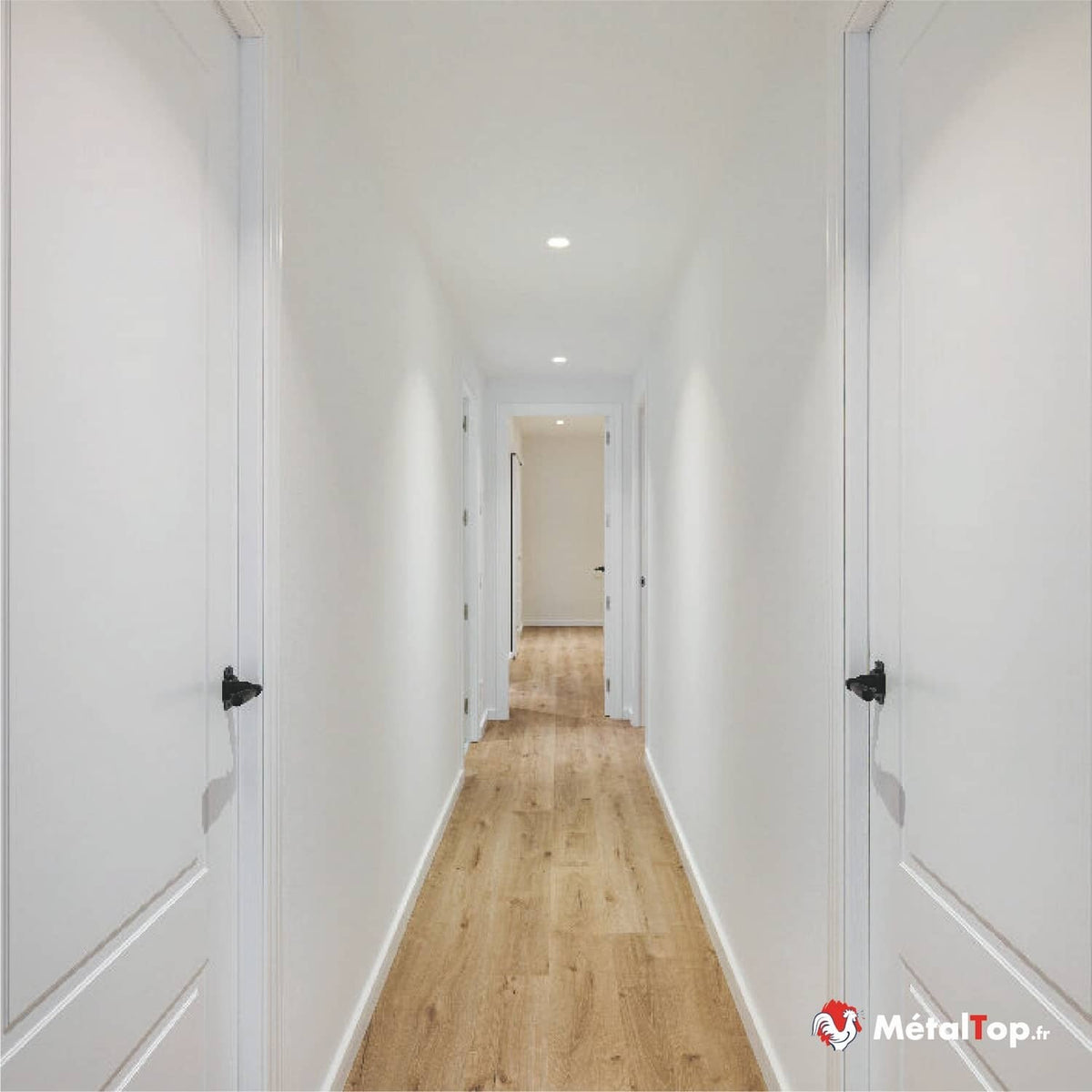 Couloir lumineux avec portes blanches, murs blancs et sol en parquet clair