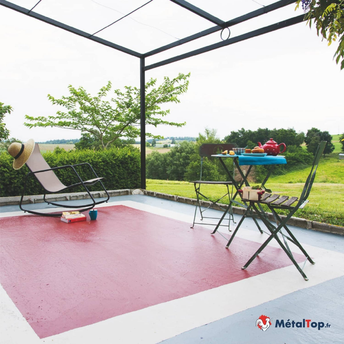 Terrasse peinte en rouge et blanc avec fauteuil à bascule et table de jardin sous une pergola