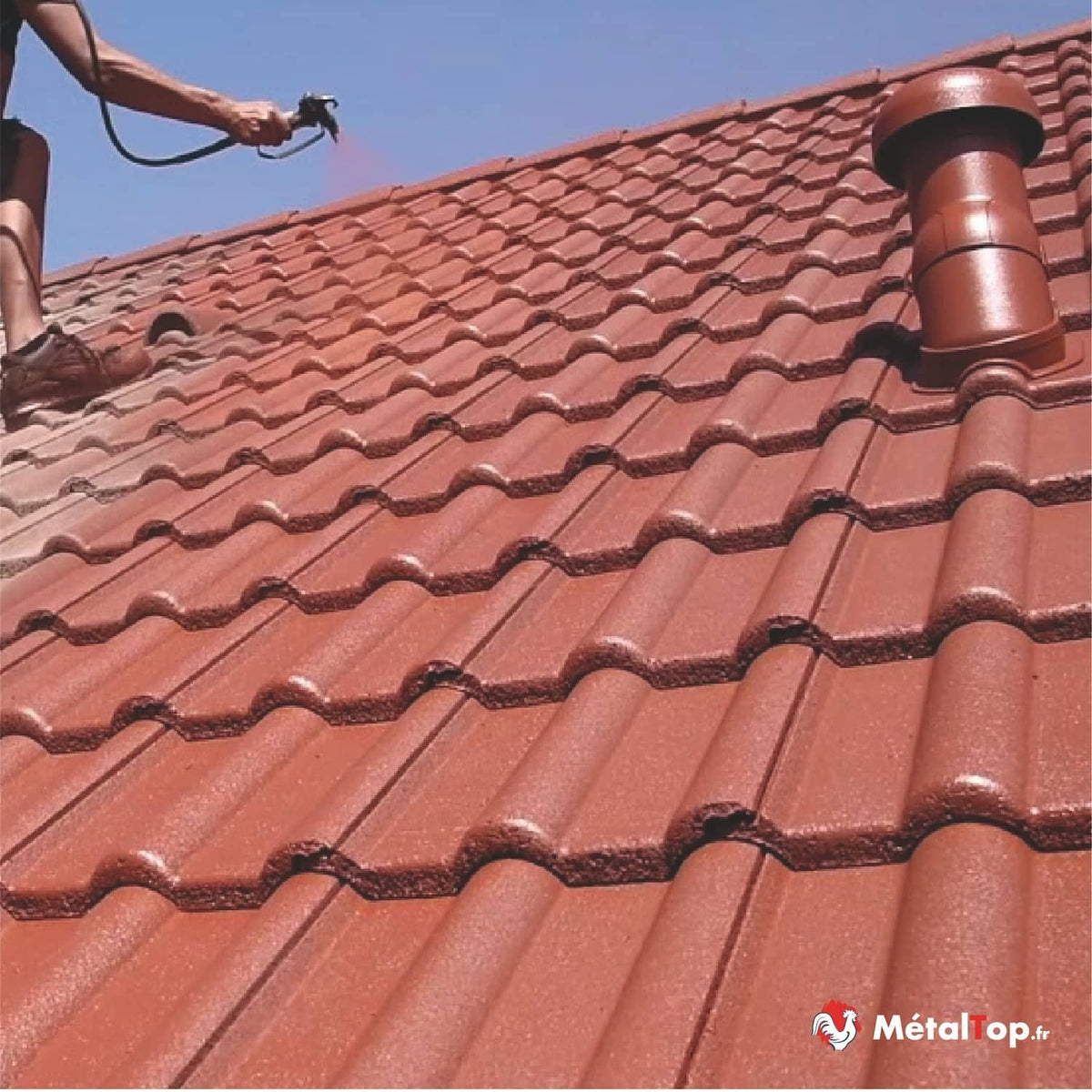 Pulvérisation de peinture sur une toiture en tuiles rouges avec une bouche de ventilation