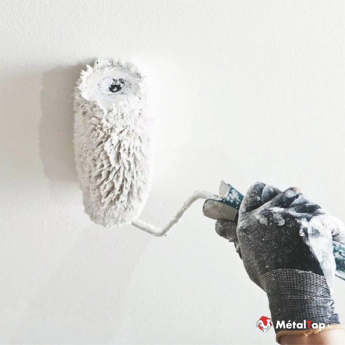 Rouleau à peinture blanc appliquant de la peinture sur un mur blanc, avec gant de protection