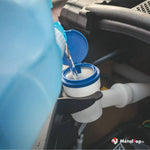 Remplissage du réservoir de liquide lave-glace dans le compartiment moteur d'une voiture