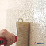 Application d'un enduit décoratif texturé sur un mur clair avec une brosse à poils