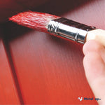 Pinceau à manche en bois appliquant une peinture rouge sur une surface en bois