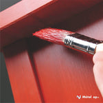 Pinceau plat chargé de peinture rouge appliquée sur un panneau de bois rouge