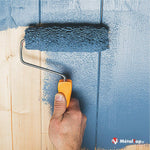 Application de peinture bleue au rouleau sur un mur en lambris de bois clair
