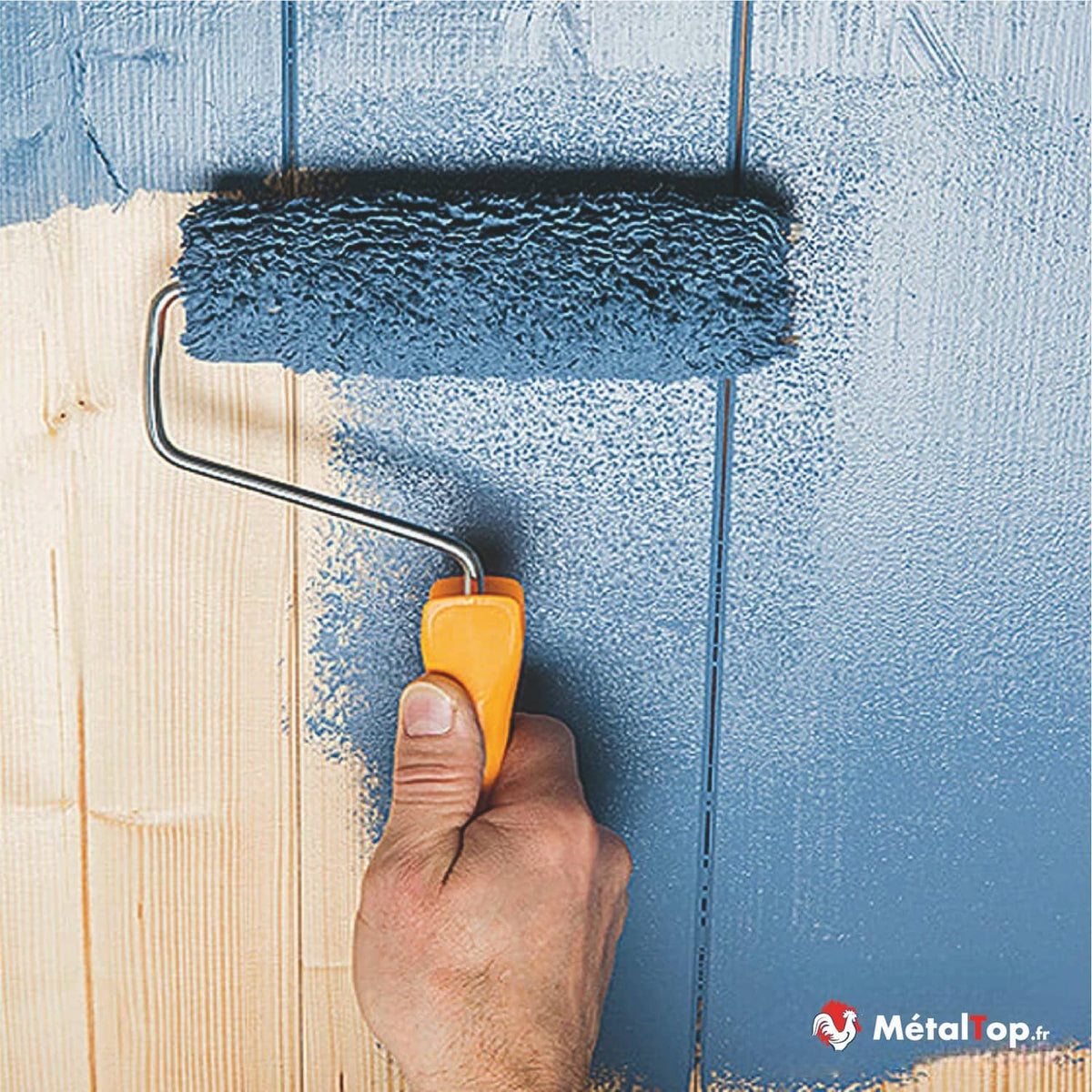 Application de peinture bleue au rouleau sur un mur en lambris de bois clair