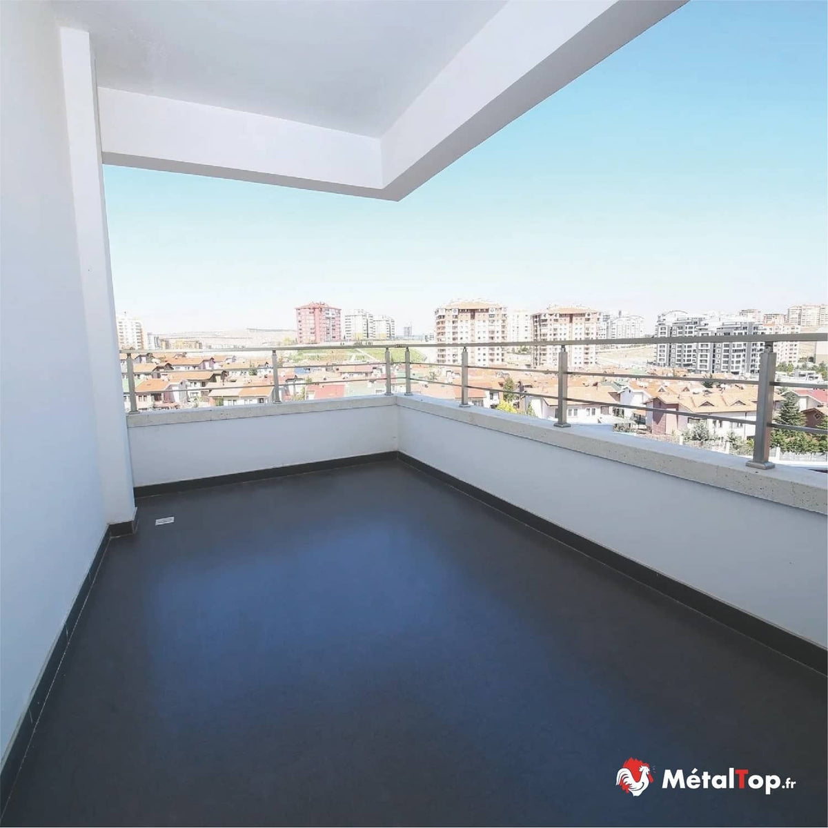 Balcon carrelé sombre avec garde-corps en inox, vue sur immeubles et maisons à toits de tuiles