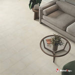 Canapé gris en tissu et table basse ronde en bois sur sol carrelé beige clair