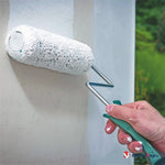 Rouleau à peinture blanc appliquant de la peinture sur un mur clair, avec manche métallique et poignée verte