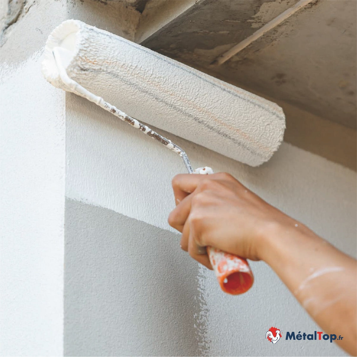 Application de peinture blanche au rouleau sur un mur en enduit clair