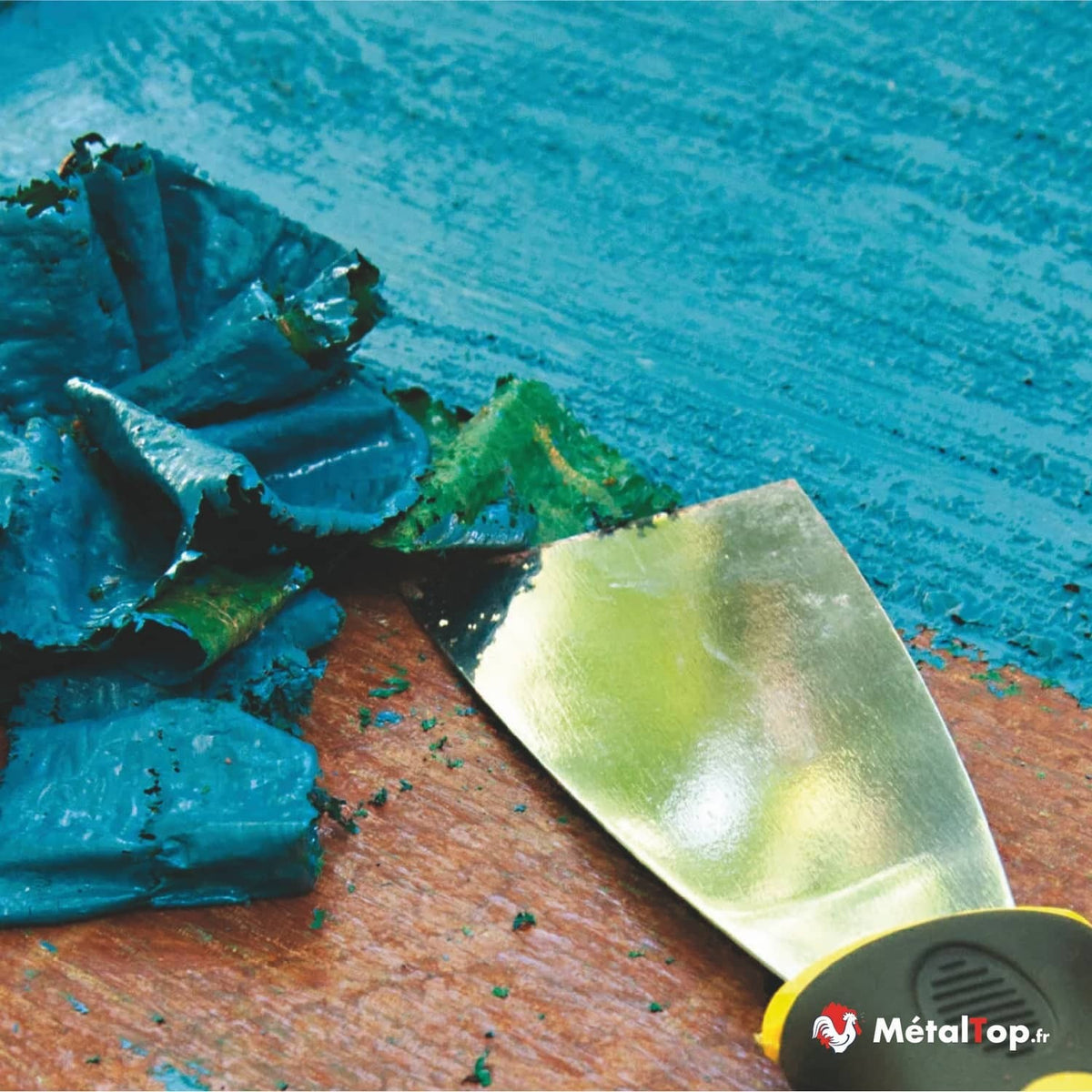 Décapage de peinture bleu turquoise à la spatule métallique sur support bois