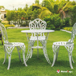 Salon de jardin blanc ajouré : table ronde et trois chaises en fonte sur pelouse verte