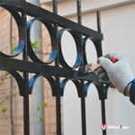Grille en fer forgé noire à motifs circulaires en cours de peinture au pinceau