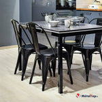 Chaises en métal noir autour d'une table de cuisine au plateau gris, avec vaisselle en verre et céramique