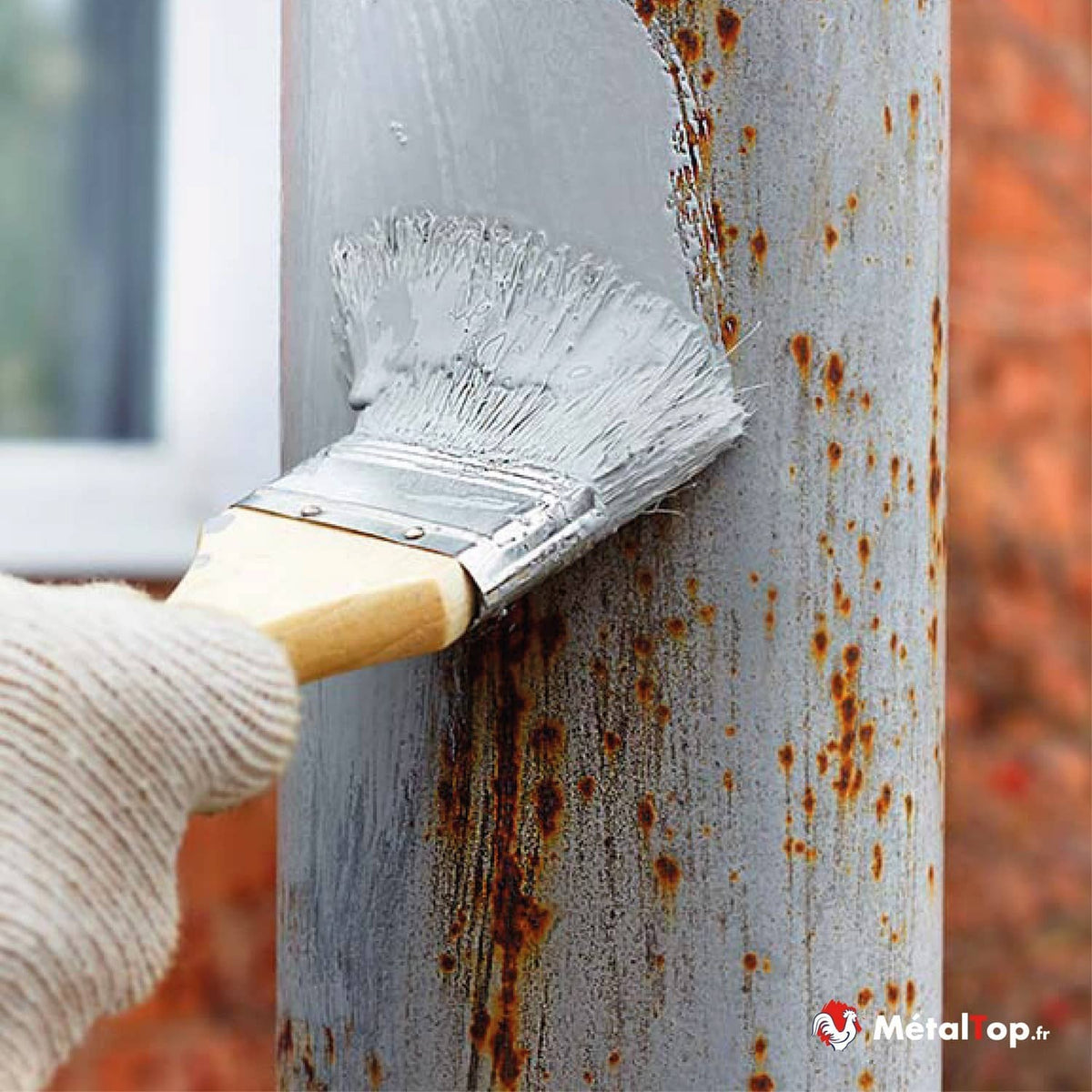 Application de peinture grise sur un poteau métallique couvert de rouille