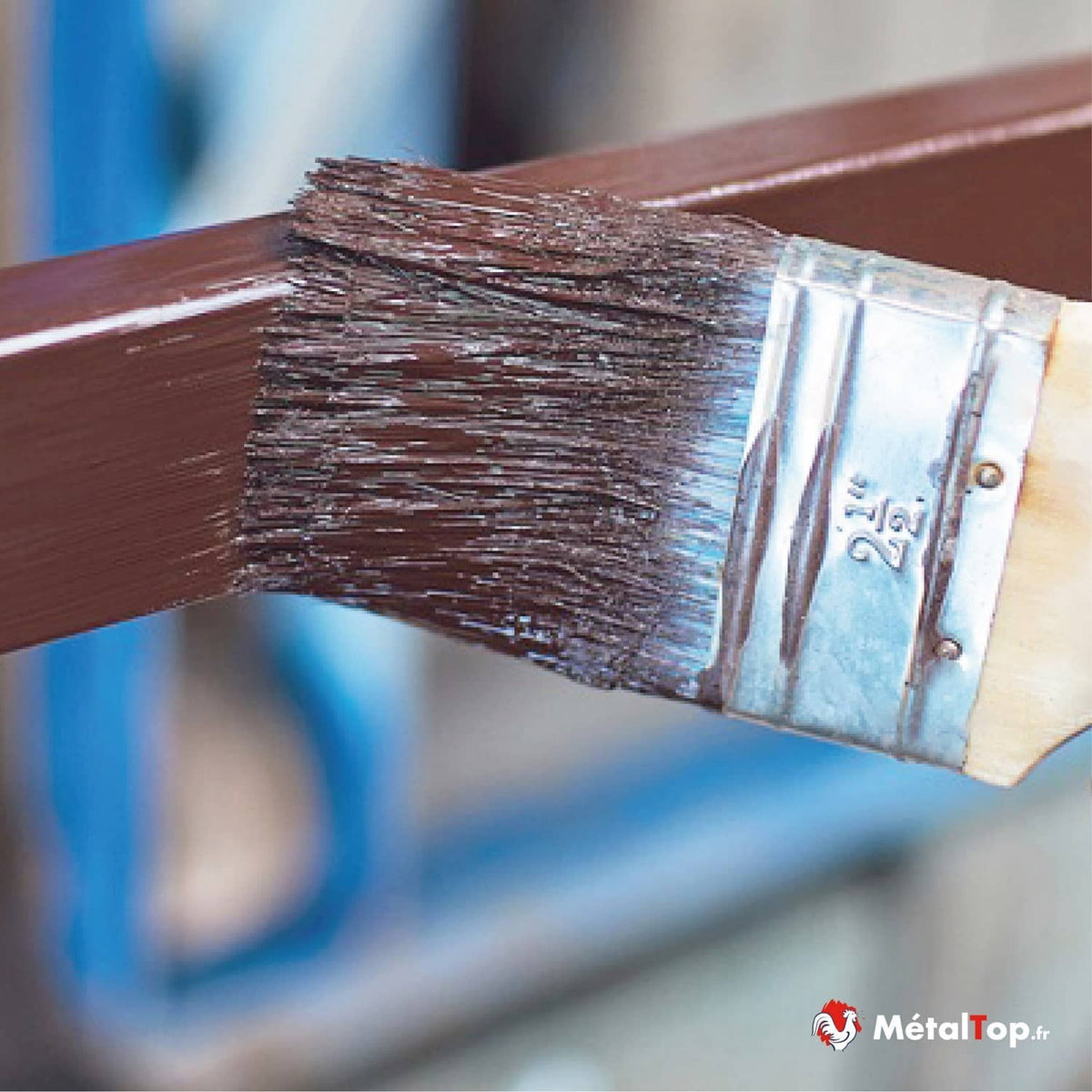 Pinceau plat appliquant une peinture marron sur une barre métallique