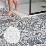 Carrelage décoratif gris et bleu à motifs, pieds nus devant une douche à paroi vitrée noire
