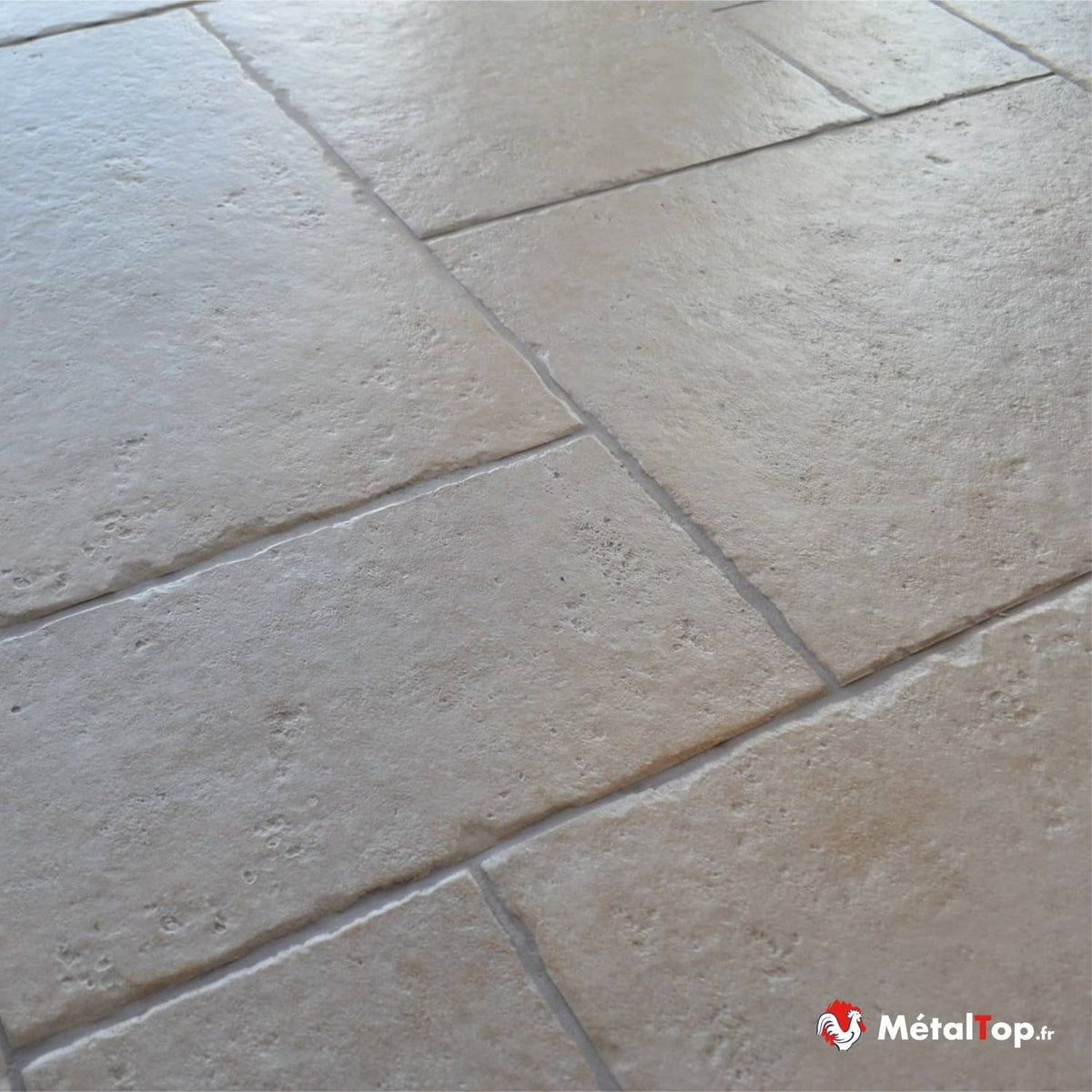 Sol en carrelage beige effet pierre, posé en grands rectangles à joints clairs