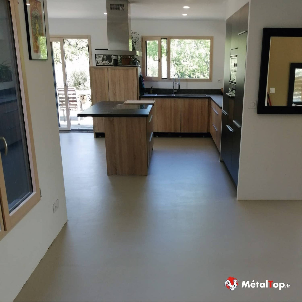 Cuisine moderne en bois clair avec îlot central, plan de travail noir et sol gris uni