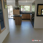 Cuisine moderne en bois clair avec îlot central, plan de travail noir et sol gris uni