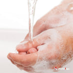 Mains savonneuses sous un filet d'eau courante, en cours de lavage