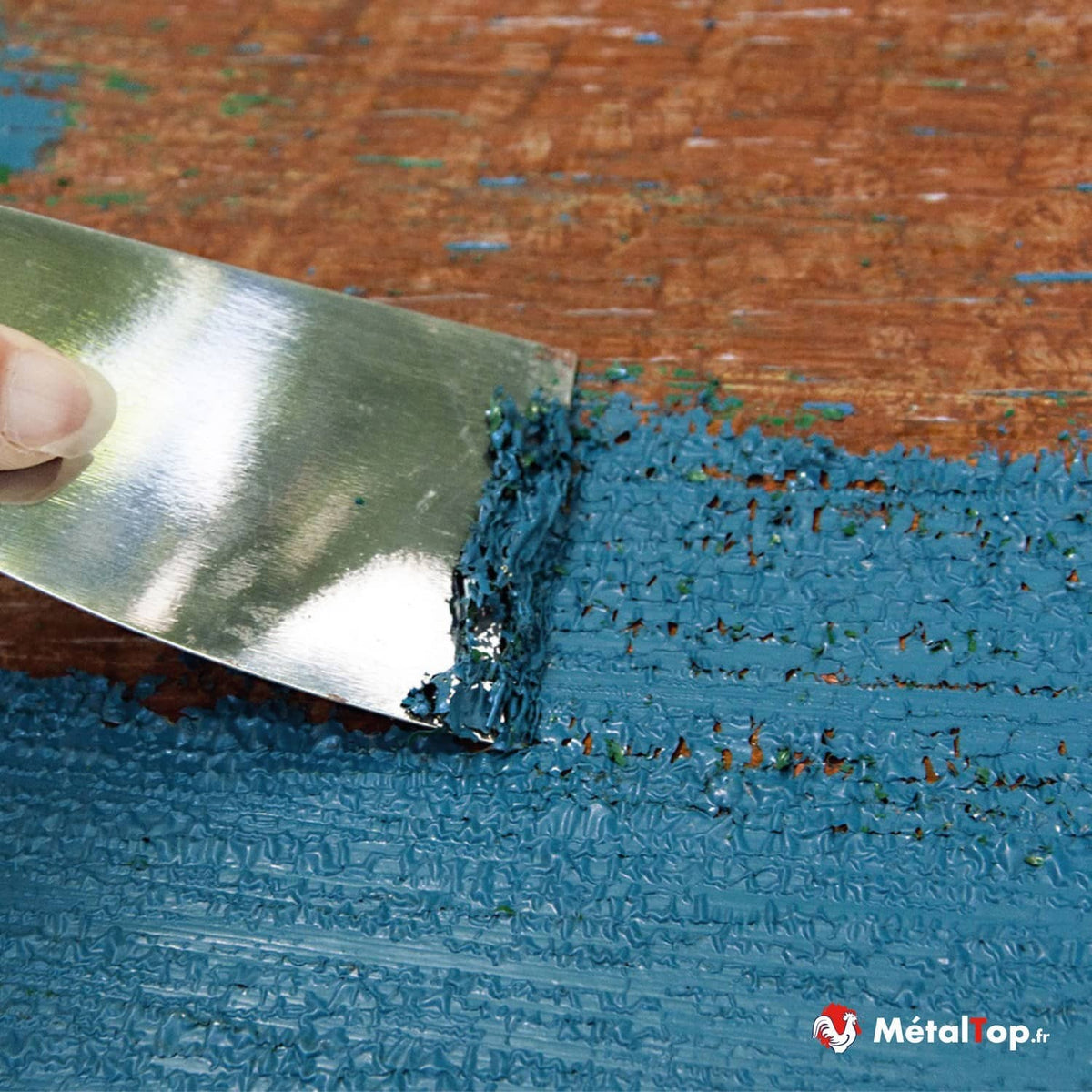 Décapage de peinture bleue écaillée à la spatule sur un bois ancien orangé