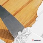 Application d'enduit blanc au couteau à enduire sur une surface en bois clair