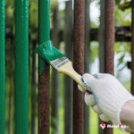 Application de peinture verte au pinceau sur une grille métallique rouillée