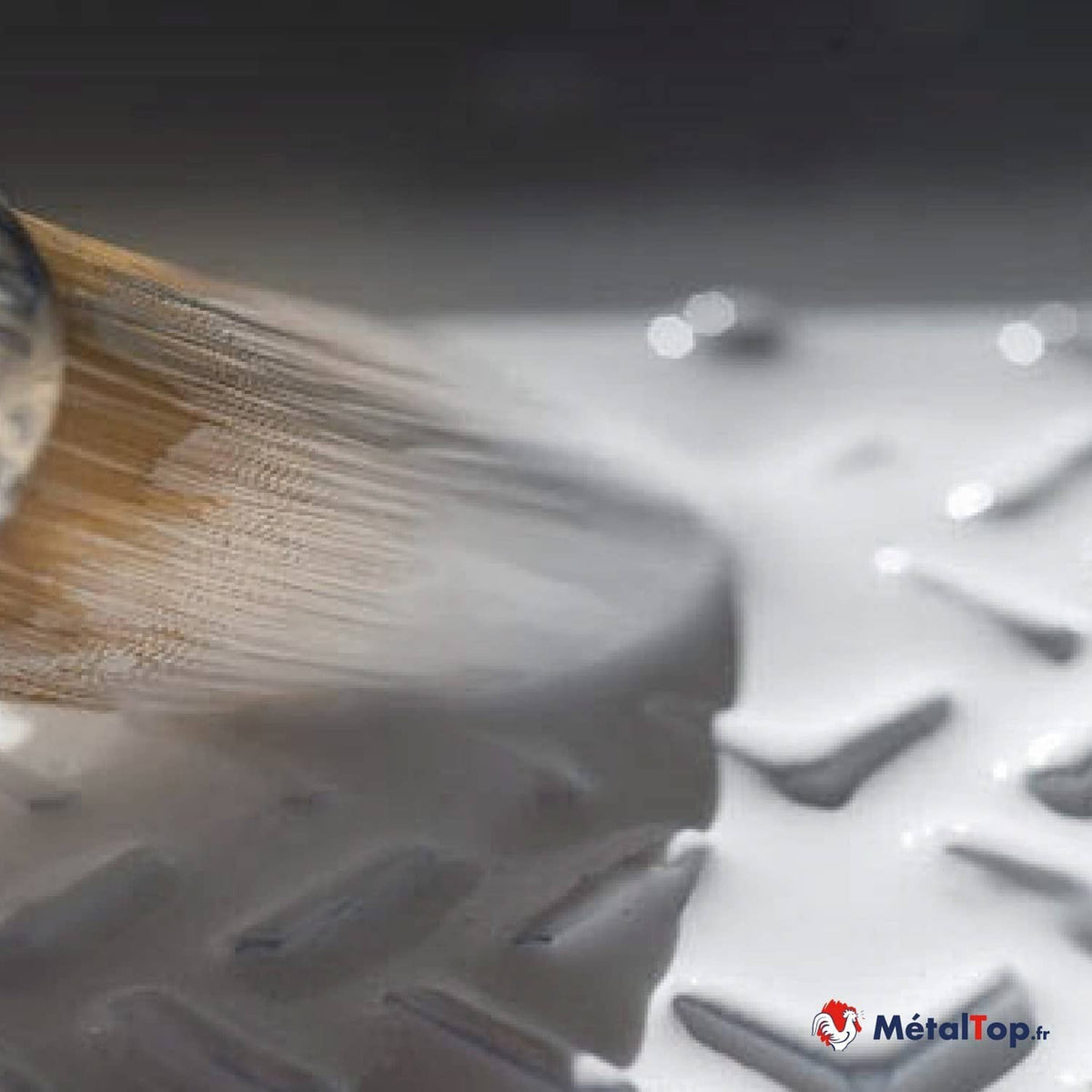 Brossage d'une tôle larmée en acier avec une brosse métallique rotative
