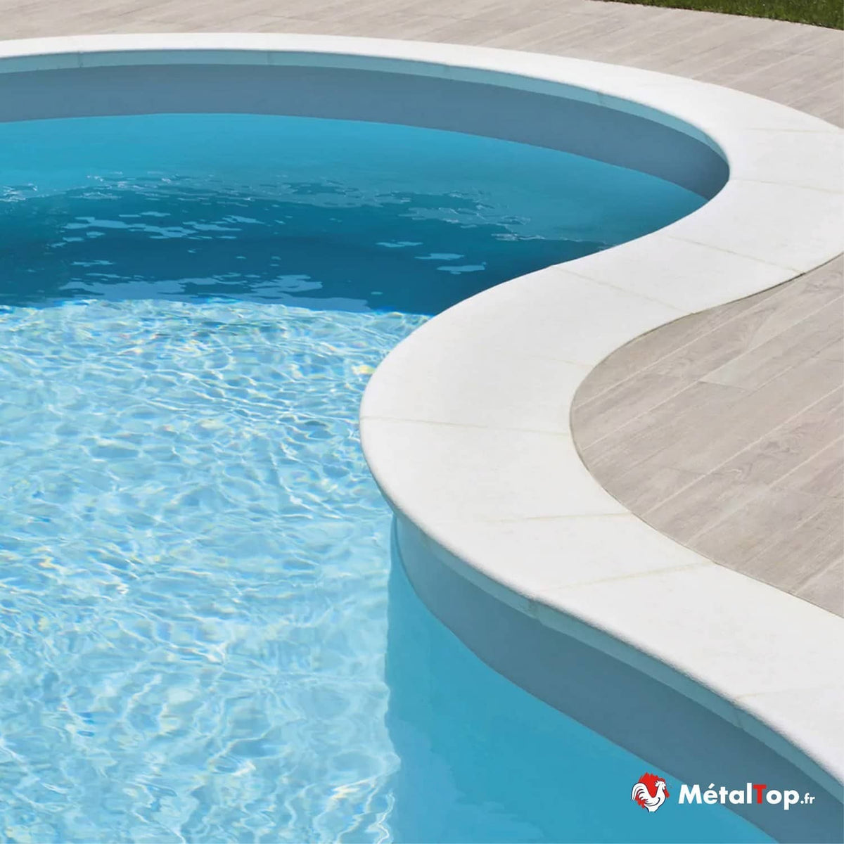 Piscine aux formes arrondies à margelle blanche et eau turquoise, bordée d'une terrasse bois clair