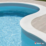Piscine aux formes arrondies à margelle blanche et eau turquoise, bordée d'une terrasse bois clair