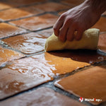 Nettoyage d'un sol en carrelage terre cuite mouillé avec un chiffon jaune, joints sombres