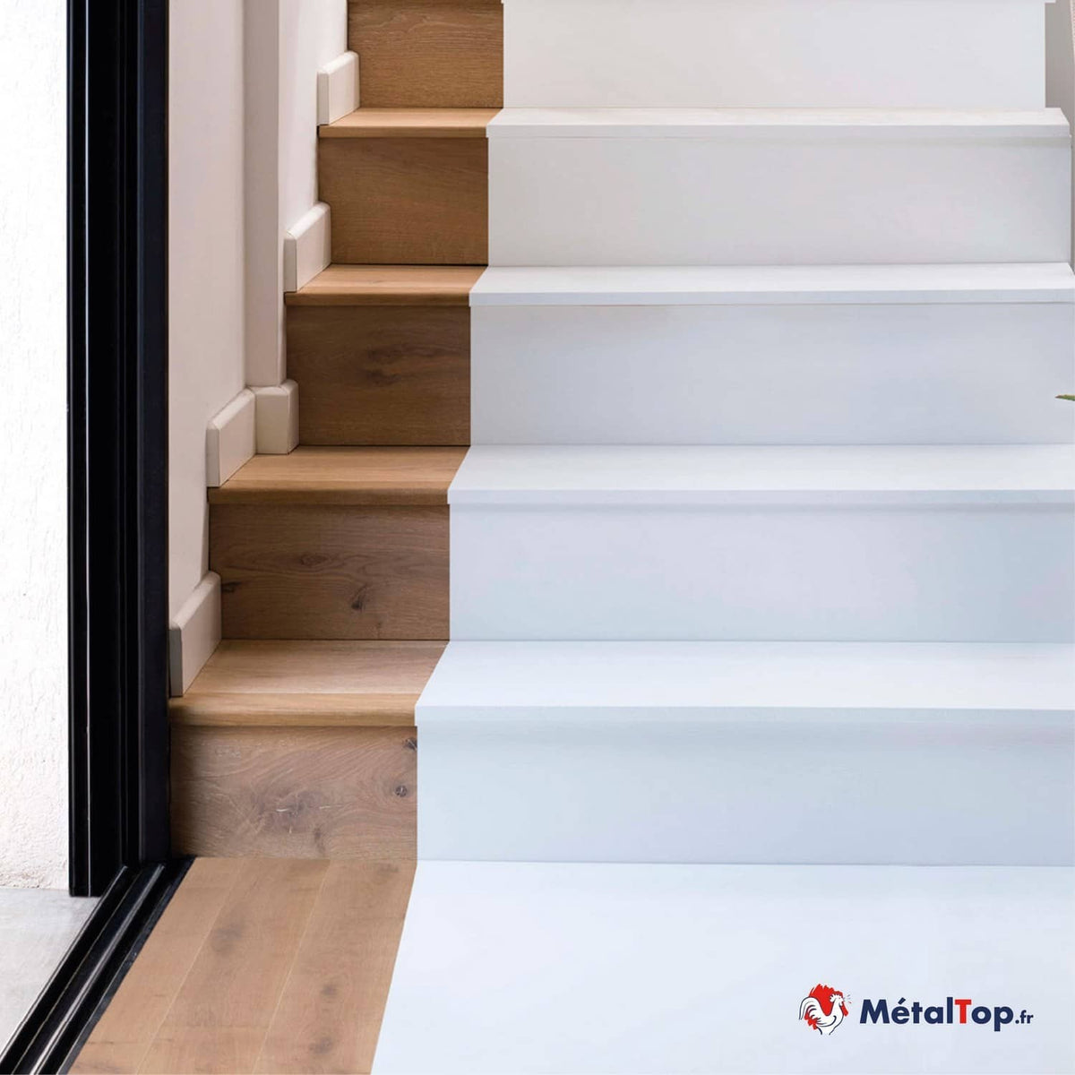 Escalier en bois naturel à gauche et peint en blanc à droite, avec sol en parquet clair