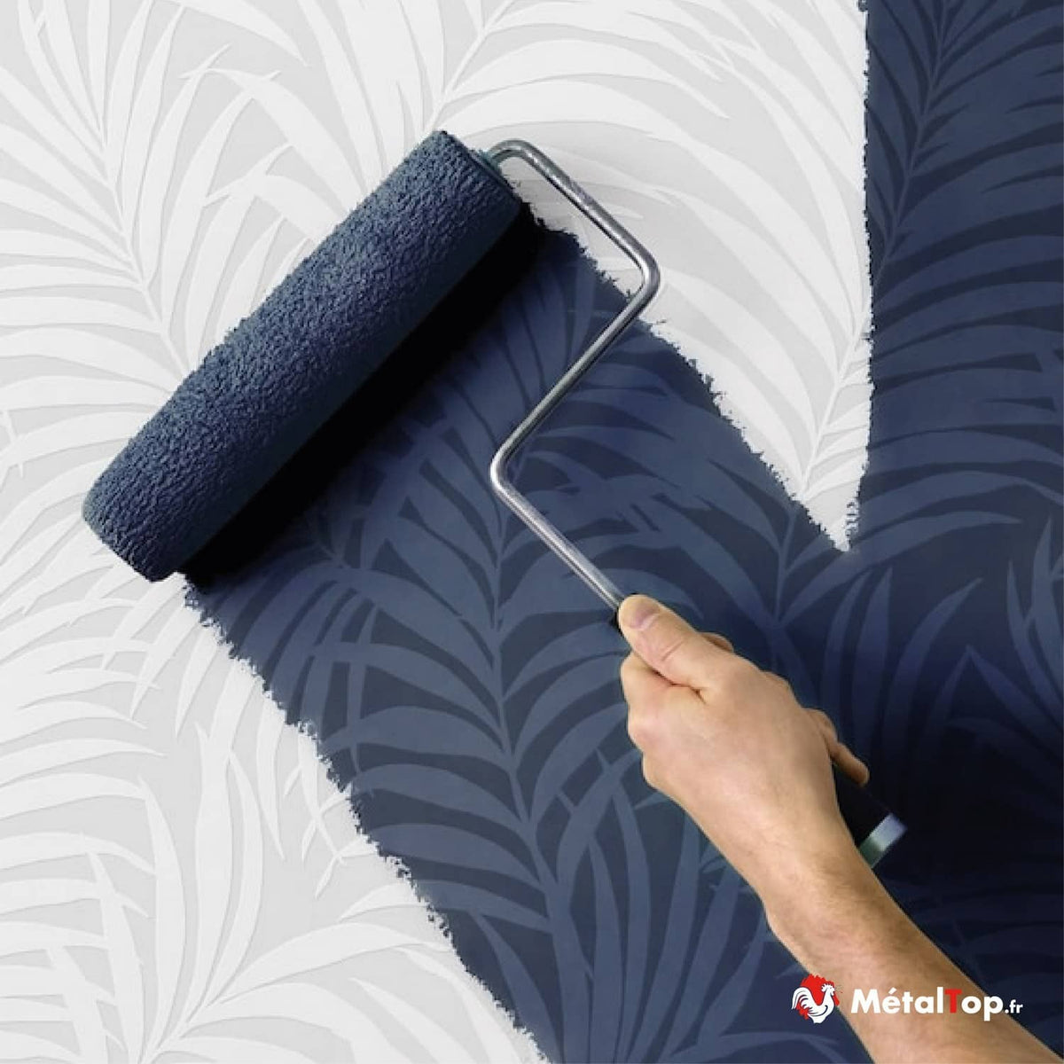 Rouleau à peinture bleu marine sur un mur à motifs de feuilles de palmier