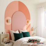 Tête de lit arquée rose et corail, deux appliques dorées, coussins verts et blancs sur un lit