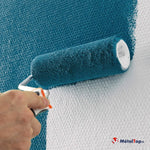 Rouleau à peinture appliquant une peinture bleu pétrole sur un mur blanc texturé